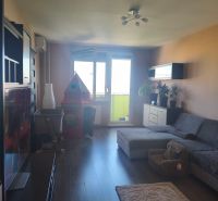 Living room in a three-room apartment with a wooden decor floor and a comfortable sofa.