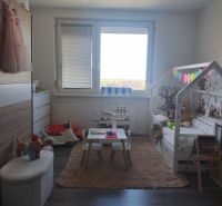 Children's room in a three-room apartment with a wooden decor floor, a play table, and a bed.
