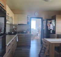 A kitchen in a 3-room apartment with a wood-patterned floor and a dining table.