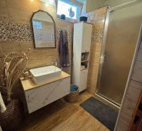 A bathroom in a family house with a sink, a shower, and a floor with a wooden decor.