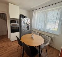 A kitchen in a family house with a wooden decor floor, a round table, and appliances.