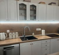 A kitchen in a family house with white cabinets and a wooden decor countertop.