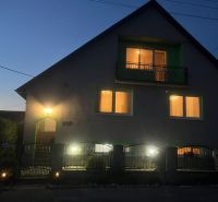 A family house on Tešmak Street in Šahy with glowing windows during the evening.