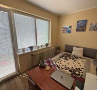 A room in a family house with a bed, a table, flowers, and decorative paintings.