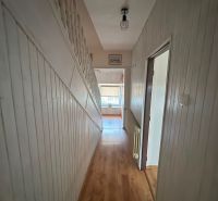 A hallway with a wooden decor floor in a family house with white walls and railing.