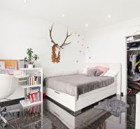 A bedroom in a family house with a desk, storage space, and wall decoration.