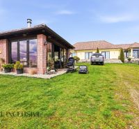 A family house in Kopanice in Krupina surrounded by a green lawn and cars in the parking lot.