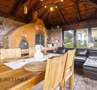 A kitchen corner in a family house with a stove, wooden table, brick wall, and seating area.