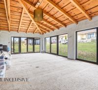 A glazed space in a family house with a wooden ceiling and a view of the garden.