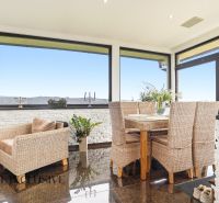 A spacious interior of a family house with rattan furniture and large windows.