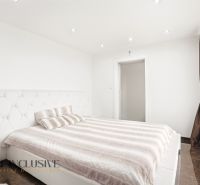 A bright bedroom in a family house with white furniture and a large window.