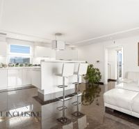A bright kitchen in a family house with white furniture and glossy tiles.