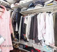 Wardrobe in a family house with lots of clothes on hangers and shelves.