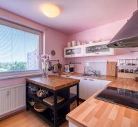 A kitchen in a 4-room apartment with light pink walls, a wooden decor floor, and a window.