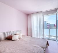 A bedroom in a 4-room apartment with soft pink walls and a balcony.