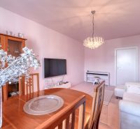 Living room of a 4-room apartment with a chandelier, sofa, and wooden furniture, decorations on the table.