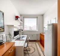 A room with a desk, computer, painting, and decorative carpet in a 4-room apartment.