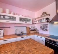 Kitchen in a 4-room apartment with wood-decor flooring, glass cabinets, appliances, pink wall.