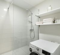Bathroom in a 4-room apartment with a washing machine, shower, and white tiles.