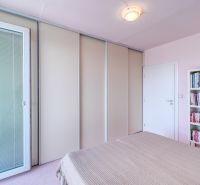 A bright bedroom with a bookshelf full of books and a wardrobe in a 4-room apartment.