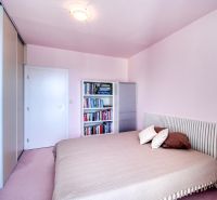 A bedroom in a 4-room apartment with a bed, a bookshelf, and a built-in wardrobe.