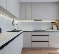 A kitchen with simple lines, white cabinets, and a wooden decor floor in a 3-room apartment.