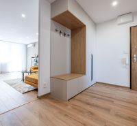 Spacious entrance area in a 3-room apartment with a wooden decor floor and light furniture.