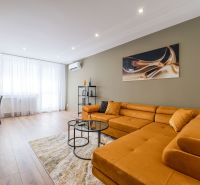 Living room in a 3-room apartment with an orange sofa and a floor with a wooden decor.