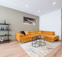 Living room in a three-room apartment with a mustard sofa and a floor with a wooden decor.