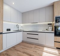 A kitchen in a 3-room apartment with a wooden decor floor and built-in appliances.
