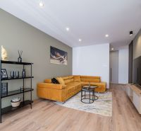 Living room in a 3-room apartment with an ochre sofa and a wooden decor floor.