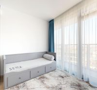 A room with a wardrobe, a gray bed, and a large window in a 4-room apartment.