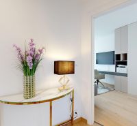 A hallway with a wooden decor floor, a table, a lamp, and flowers in a 4-room apartment.