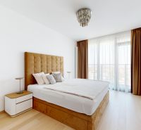 Bedroom with a light wood-patterned floor, a large headboard, and curtains in a four-room apartment.