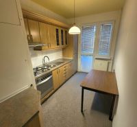 A kitchen in a 3-room apartment with wooden furniture, a dining table, and white lighting.