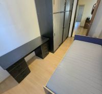 A bedroom in a three-room apartment with a wooden decor floor, a wardrobe, and a bed.