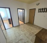 A hallway with light tiles and a wooden shoe cabinet in a 3-room apartment.