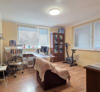 A room in a family house with a desk, wooden decor flooring, and an exercise bike.