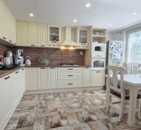 A kitchen with brick cladding and a wooden decor floor in a family house.