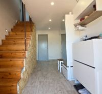 A hallway in a family house with a wooden staircase and a floor with a wooden decor.