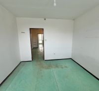 A room in a 3-room apartment with white walls and a colorful floor.