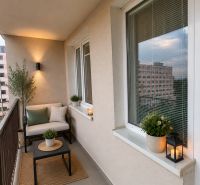 Cozy balcony with a sofa, table, and decorative plants in a 3-room apartment.