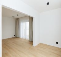 A room in a 3-room apartment with a wooden decor floor, curtains, and a French window.