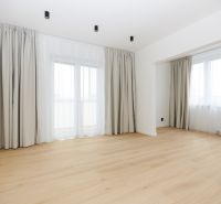 A room in a 3-room apartment with a wooden decor floor and large windows.