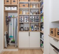 A pantry organized in a 3-room apartment with shelves and a floor with a wooden decor.