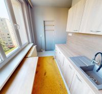 A kitchen in a 3-room apartment with wooden decor cabinets and a large window.