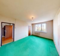 A room in a 3-room apartment with a green carpet and a large window.