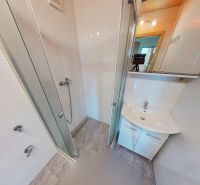A bathroom with white tiles and a shower in a 3-room apartment.