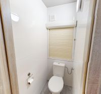 A toilet with white tiles and blinds in a 3-room apartment.