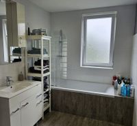 Bathroom in a 4-room apartment with a bathtub, a towel rack, and a wooden decor floor.